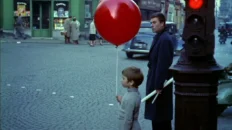 The Red Balloon 1956 film scene showing a young boy with a bright red balloon in Paris streets
